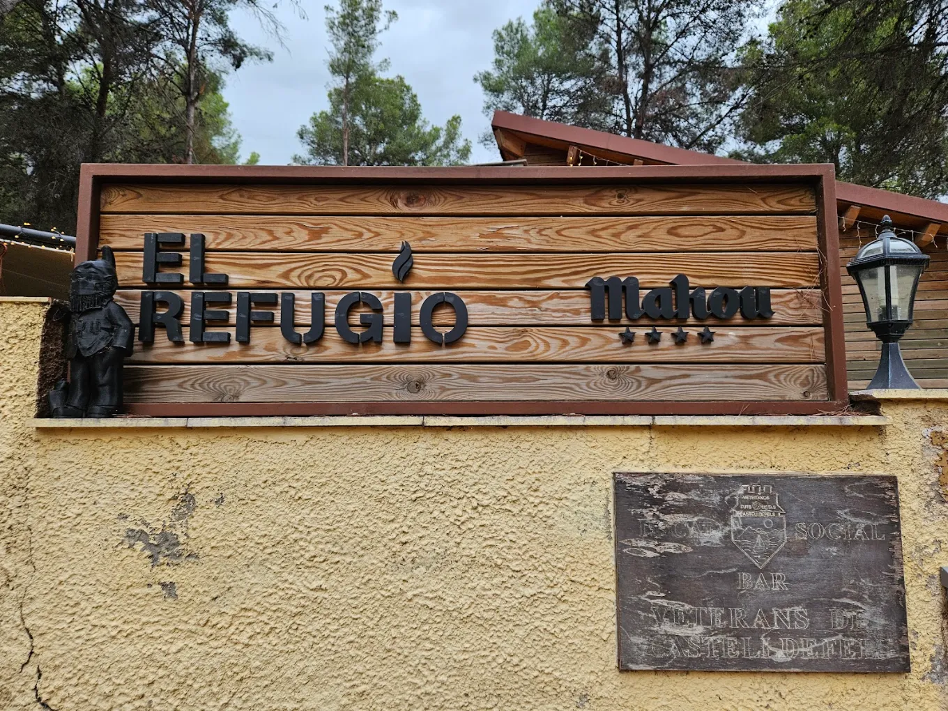 Cartel de El Refugio en madera junto al pinar